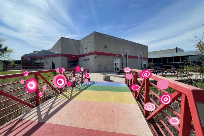 The pink circular elements create a strong contrast with the straight, rigid structure of the bridge. Their playful, bouncing appearance draws attention to the railings, making the bridge feel energetic.